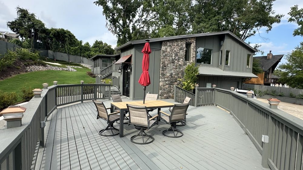 The main home’s deck with an outdoor dining table, four chairs, and a red patio umbrella