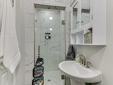 The Dogwood's compact bath with a corner shower enclosure and pedestal sink — shower only, no tub