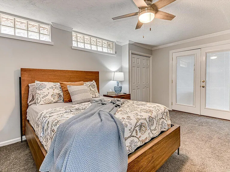 A Dogwood bedroom with an arched upholstered headboard and floral bedding