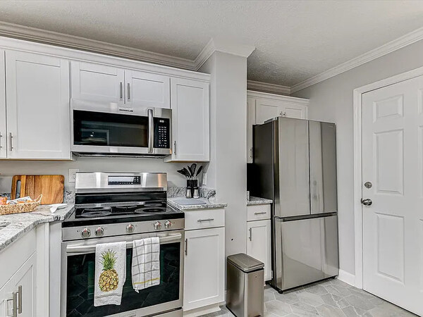 The kitchen of The Dogwood apartment with cabinetry, range and eat-in corner