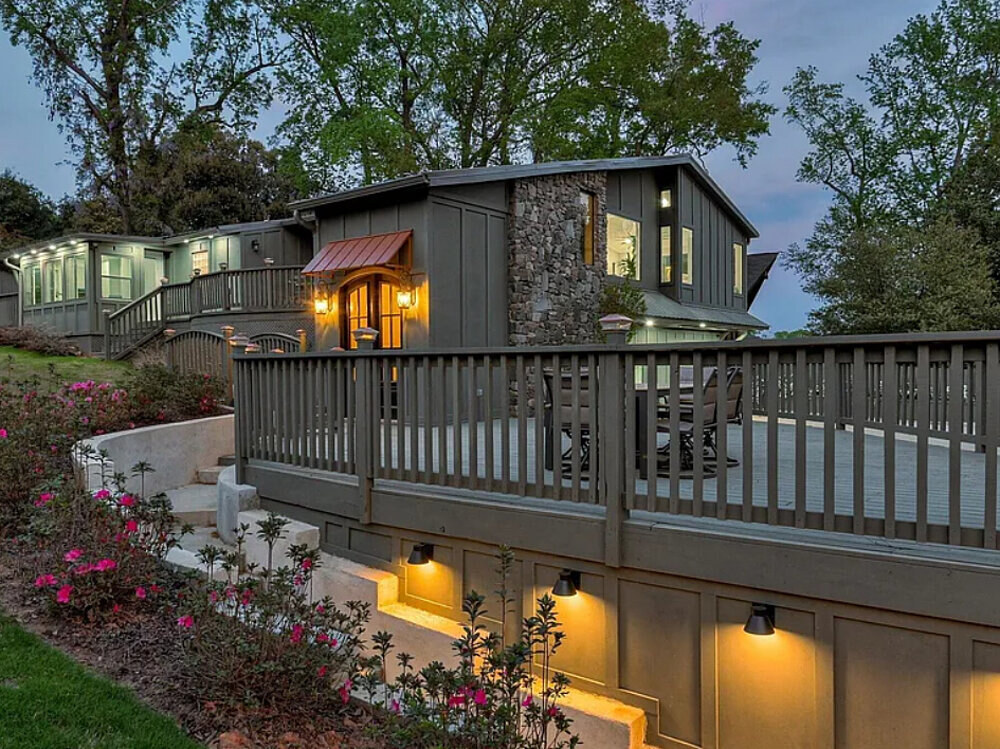The main home at twilight with warm interior light and pink azaleas along the front deck