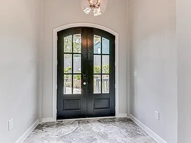 Arched entry hall with a stone-tiled floor, lantern chandelier, and a round console table
