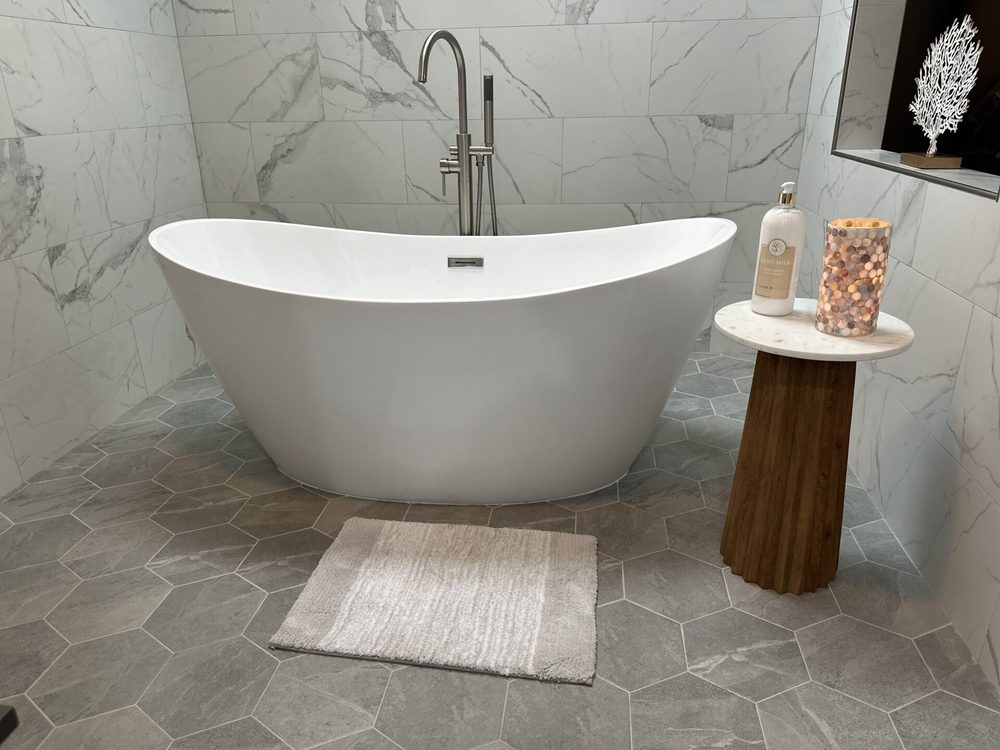 Freestanding oval soaking tub against marble tile in the master bath