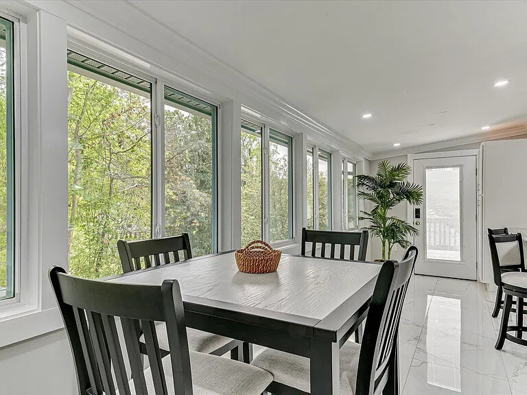 Sunroom with navy woven armchairs and a wall of windows looking onto the green lawn
